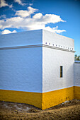 Ein schön erhaltener Geräteschuppen mit weißen und gelben Wänden in der malerischen Provinz Sevilla, Spanien, unter einem strahlenden Himmel.