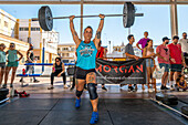 Participants lifting heavy weights during a crossfit competition in Sevilla, España. Event showcases strength, determination, and athleticism.