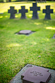 Close-up view of gravestones at the German military cemetery in Normandy, France, commemorating fallen soldiers. Peaceful and solemn atmosphere.