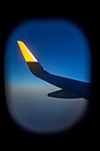 Airplane wing end illuminated by the rising sun through a window at sunrise, symbolizing travel and new beginnings.