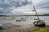 A scene of boats stranded at low tide in Vannes, Brittany, France. Overcast sky reflecting peaceful coastal charm.