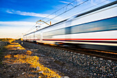 A high-speed train blurs by on the tracks through the countryside near Carrion de los Cespedes in the province of Sevilla, Andalusia, Spain.