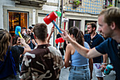 Begrüßung von Menschen mit welkem Lauch und Plastikhämmern während des Johannisfestes (Festa de Sao Joao do Porto ) im Hochsommer, in der Nacht zum 23. Juni (Johannisnacht), in der Stadt Porto, Portugal