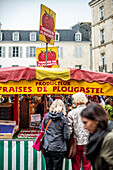 Käufer stöbern an einem Marktstand in Vannes, Bretagne, Frankreich. Der Stand verkauft frische Produkte, darunter Erdbeeren.