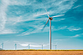 Windturbinen zur Erzeugung erneuerbarer Energie vor einem strahlend blauen Himmel in Tarifa, Spanien. Das Bild fasst das Konzept der nachhaltigen Energie zusammen.