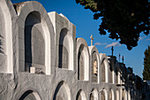 Blick auf den katholischen Friedhof in Aznalcazar, Provinz Sevilla, Andalusien, Spanien. Das Bild zeigt Grabsteine und Kreuze unter einem klaren blauen Himmel.