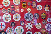 Colorful emblems of Holy Week brotherhoods for sale in a shop window in Seville, Spain. Represents religious tradition and cultural heritage.