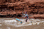 A young woman paddle boarding in the white water of White's Rapid on the Colorado River near Moab, Utah.