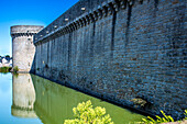 Picturesque view of the historic Guerande wall and its surrounding moat on a sunny day in Brittany, France.