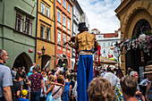 Künstlerin spielt Geige, während sie auf Stelzen bei der Puppenparade vom Marienplatz zum Altstädter Ring während des Prager Straßentheaterfestivals Behind the Door läuft, Prag, Tschechische Republik