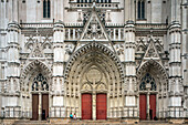 Tourists walking and exploring the magnificent St Pierre et St Paul Cathedral at Saint Pierre Square in Nantes, France.