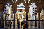 Tourists taking in the intricate details of the mihrab at the historic Cordoba Mosque in Andalusia, Spain.