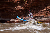 A young woman paddle boarding in the white water of White's Rapid on the Colorado River near Moab, Utah.