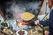 Authentische Zubereitung von Migas Serranas nach traditionellen Methoden in Villaviciosa de Córdoba, Andalusien, Spanien. Feuergekochtes Gericht mit lokalen Zutaten.