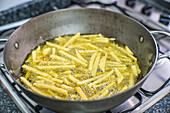 Close-up of a traditional iron pot with potatoes being fried in olive oil.