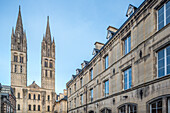 Die historische Männerabtei in Caen mit ihren gotischen Türmen vor einem heiteren Himmel.