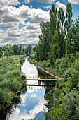 Naturszene eines Bewässerungskanals in Puente del Congosto, einer Stadt in der Provinz Salamanca, Spanien, umgeben von Bäumen und Grünflächen.