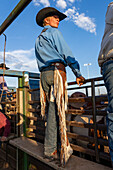 Saddle bronc cowboy Josh Davison in his fringed leather chaps stands at the bucking chutes at a rodeo in rural Utah.