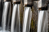 Nahaufnahme des Wassers, das aus der Fuente de los 12 Canos in Fuenteheridos, Huelva, Andalusien, Spanien, fließt.