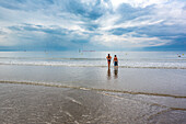 Zwei Kinder genießen ihre Zeit am Strand in Le Havre, Frankreich, unter einem bewölkten Himmel.