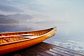 Holzkanu auf dem Dock am ruhigen Lake Placid, bedeckt mit Nebel