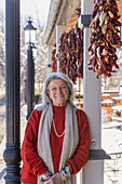 Portrait of smiling woman leaning against column at sidewalk cafe