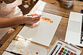 Close-up of teenage girl painting with watercolors at table