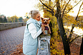 Frau mit Yorkshire Terrier am Fluss im Herbst