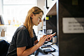 Woman looking at smart phone at desk in office