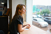 Woman leaning on window sill and looking through window