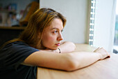 Woman leaning on window sill and looking through window