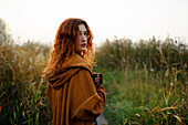 Portrait of woman with red hair standing in grassy field