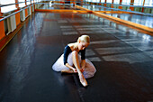 Ballerina sitting on floor in ballet studio