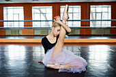 Ballerina sitzend auf dem Boden im Ballettstudio