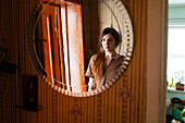 Portrait of woman reflected in round mirror