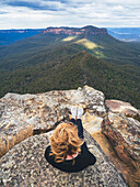 Overhead view of woman sitting on top on mountain, looking at view