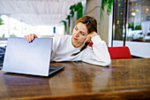 Woman looking at laptop at cafe table