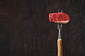 Raw beef steak on a meat fork