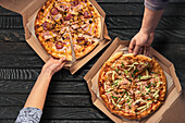 Two pizzas with different toppings in cardboard boxes