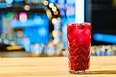 Gin cocktail with cherry juice and ice cubes