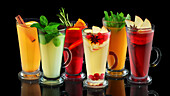 Various fruit teas in glasses with fruit, herbs and spices