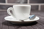 Steaming espresso in a white cup with spoon