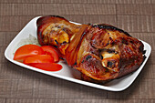 Roasted pork knuckle with onion and tomato slices