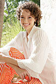 Brunette woman in cream-coloured blouse and orange-coloured patterned trousers