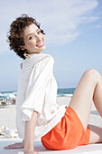 Brunette woman in cream-coloured blouse and orange shorts