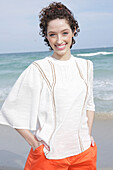 Brunette woman in cream-coloured blouse and orange shorts