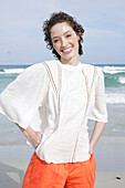 Brunette woman in cream-coloured blouse and orange shorts