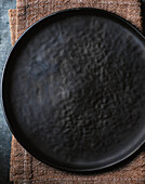 Dark ceramic plate on brown linen napkin