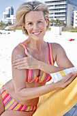 Woman on the beach applying sun cream