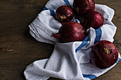 Whole red onions on a rustic tea towel